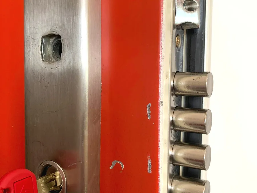Open lock on a red door, metal rods visible