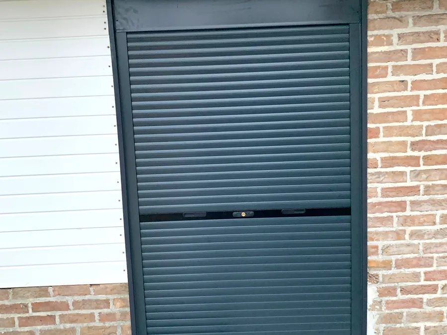 Dark grey roller shutter on a brick facade